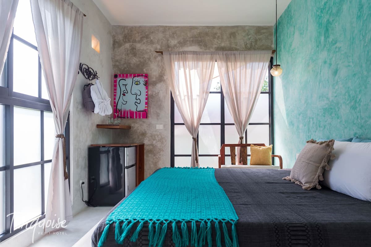 A bedroom with a bed, teal throw blanket, and a teal accent wall.