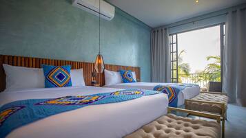 Hotelkamer met twee bedden, een houten hoofdeinde, een groot raam met gordijnen en uitzicht op palmbomen.
