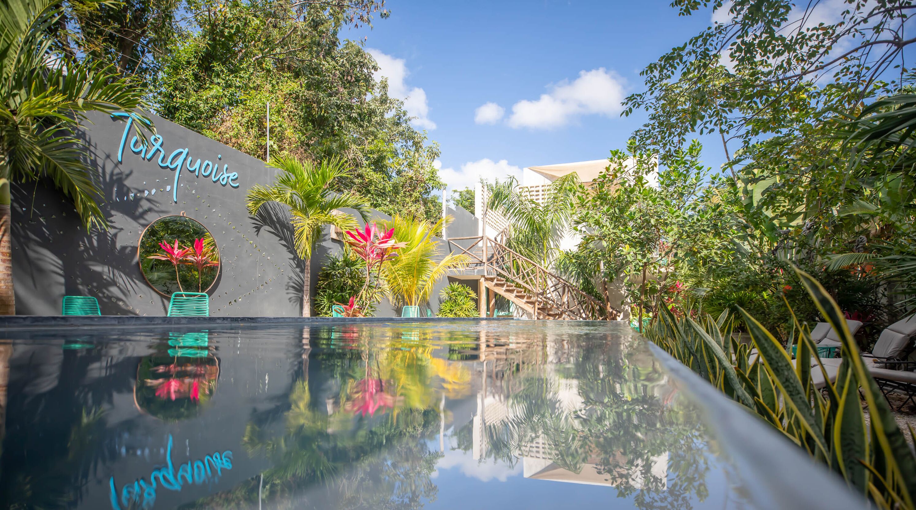 A pool area with a sign reading "Turquoise" and a reflection of the sky and trees.