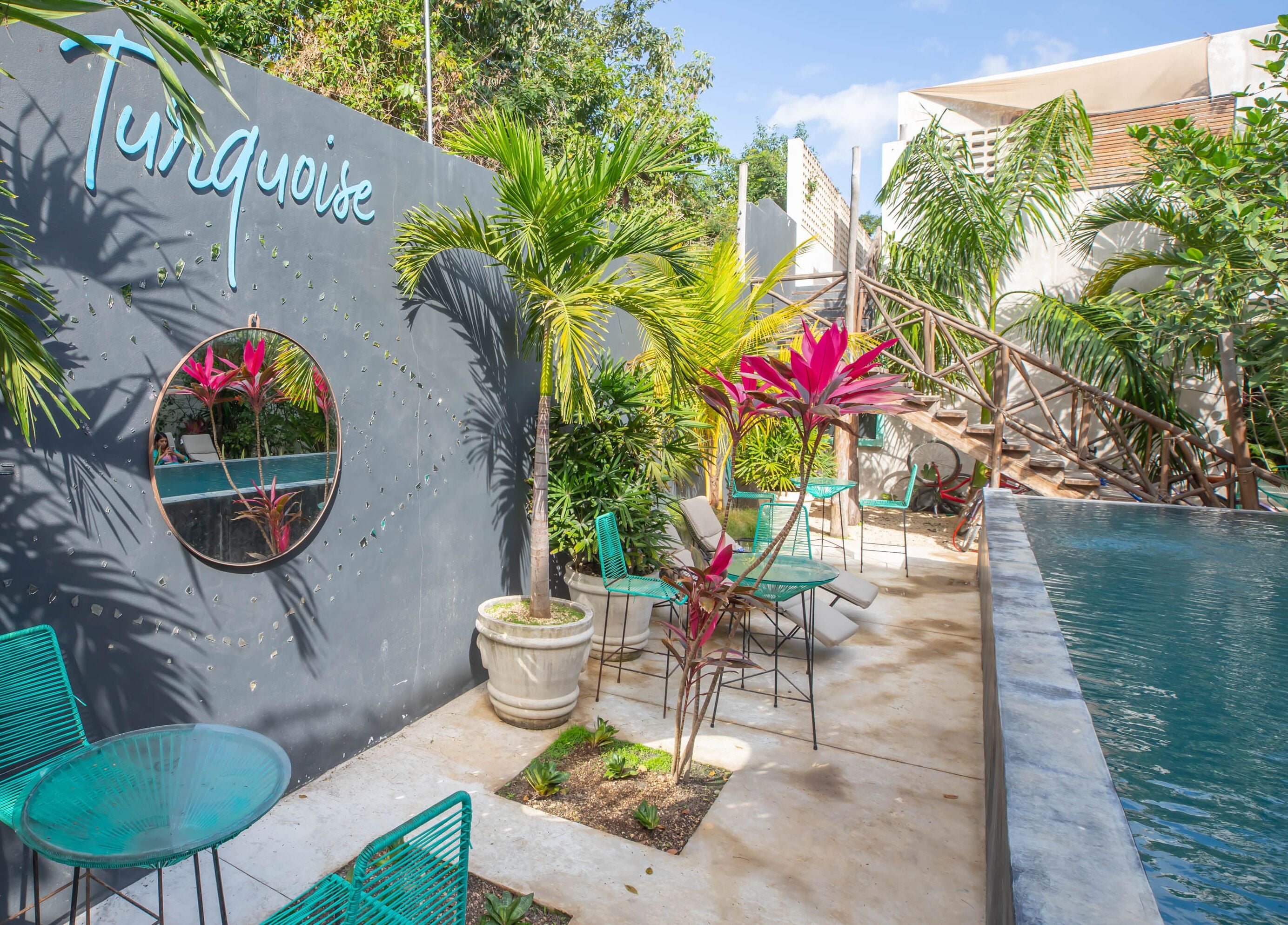 A poolside area with a sign reading "Turquoise," surrounded by greenery and outdoor seating.