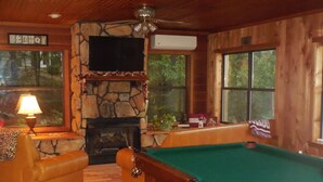 Una habitación acogedora con chimenea de piedra, mesa de billar y asientos cómodos.