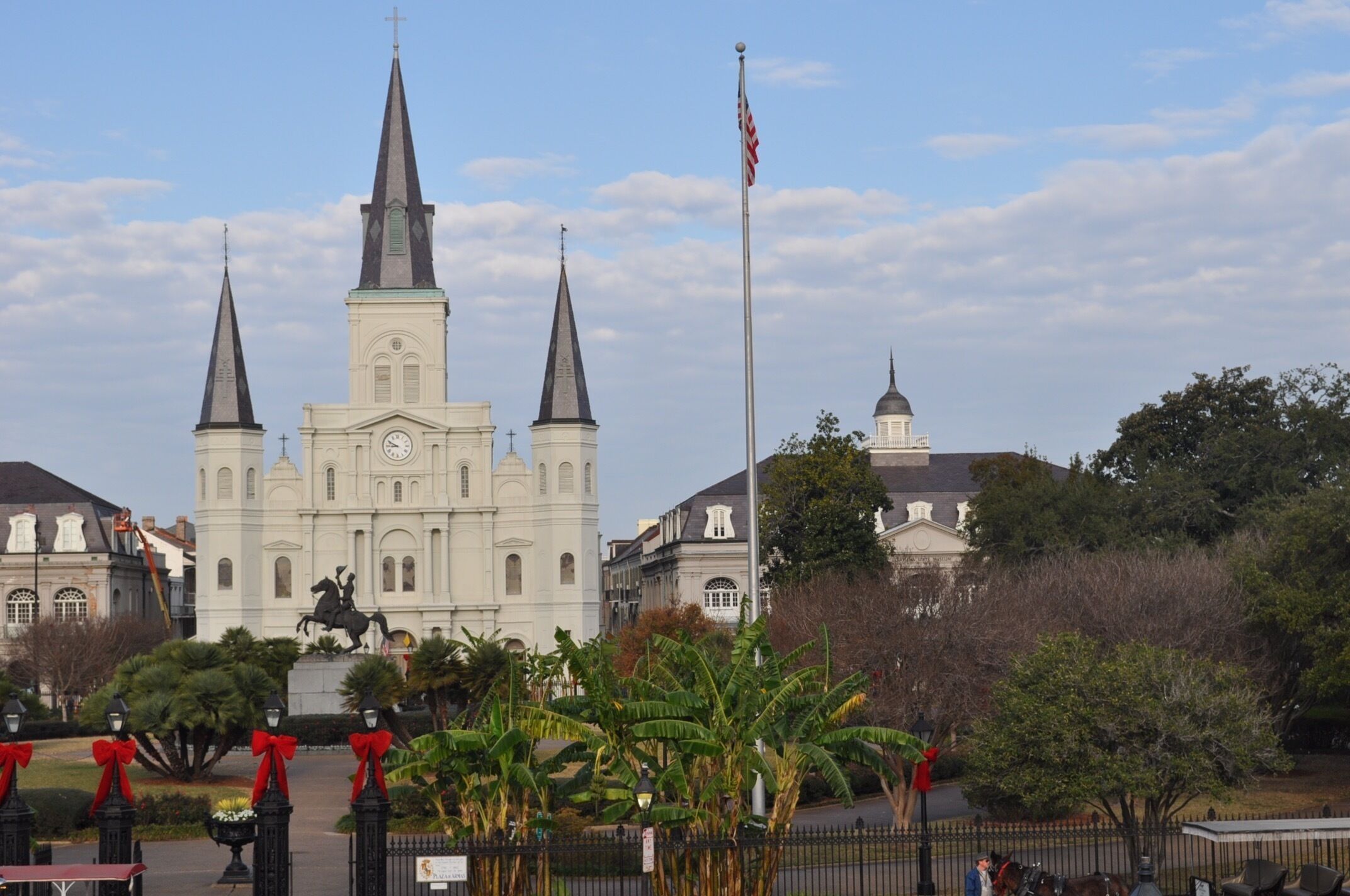 A historic church with three spires, a statue in front, and a flagpole.