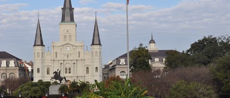 A historic church with three spires, a statue in front, and a flagpole.