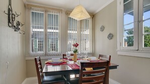 Un coin repas avec une table dressée pour quatre personnes, un luminaire suspendu et une fenêtre donnant sur un paysage verdoyant.