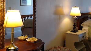 A hotel room with a large mirror, two bedside lamps, a wooden nightstand, a small chair, and a bed with a headboard. - The Garden Suite has beautiful views of forests and pastures! It is dog friendly (Ferndale)