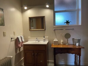 A bathroom with a wooden vanity, a mirror, a sink, a towel rack, a window with a view, and a radiator. - The Garden Suite has beautiful views of forests and pastures! It is dog friendly (Ferndale)