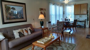 A living room with a sofa, a coffee table, and a dining area with chairs and a table.