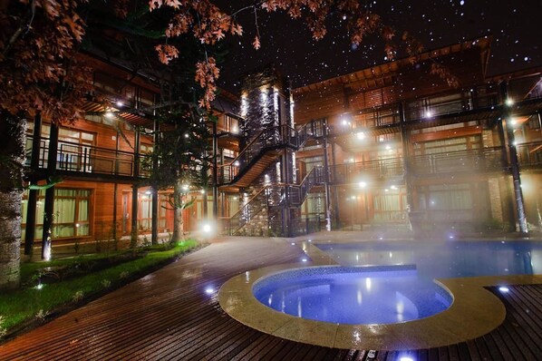 A hotel with a hot tub, wooden deck, and a staircase leading to the upper levels.