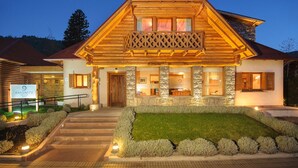Un chalet en bois avec une façade en pierre, un balcon et une entrée bien éclairée.