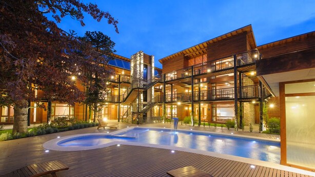 Un hôtel moderne doté d’une piscine, d’une terrasse en bois et de plusieurs balcons.