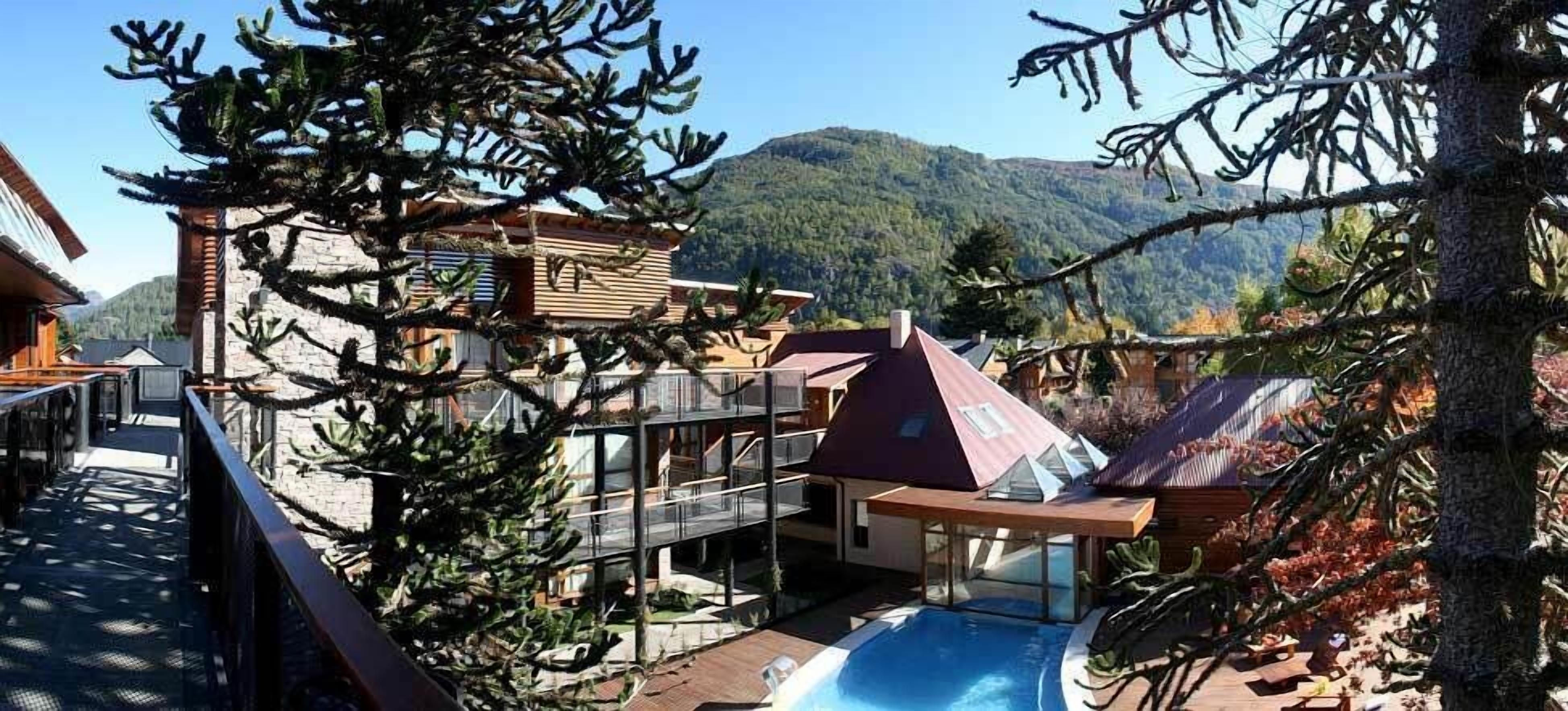 A resort with a pool, multiple buildings, and a mountainous backdrop.