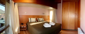 A hotel room with a bed, pillows, a nightstand, a telephone, and a wardrobe.