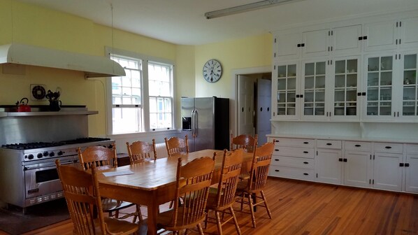 A kitchen with a dining table, chairs, a stove, oven, refrigerator, and cabinets.