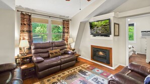 Una sala de estar acogedora con chimenea, sofás de cuero y ventilador de techo.