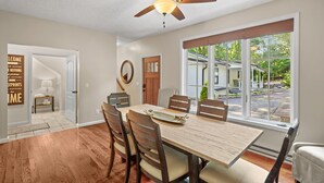 Comedor con mesa y sillas de madera, ventilador de techo y vista al exterior.