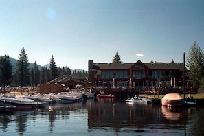 A marina with boats docked in front of a large building with a prominent roof and multiple windows.