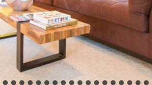 A living room with a brown sofa, a wooden coffee table, and a window with blinds.