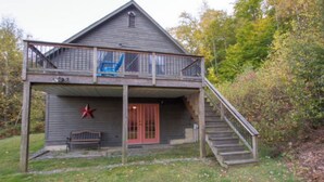 A two-story wooden cabin with a balcony, a red door, and a star decoration.
