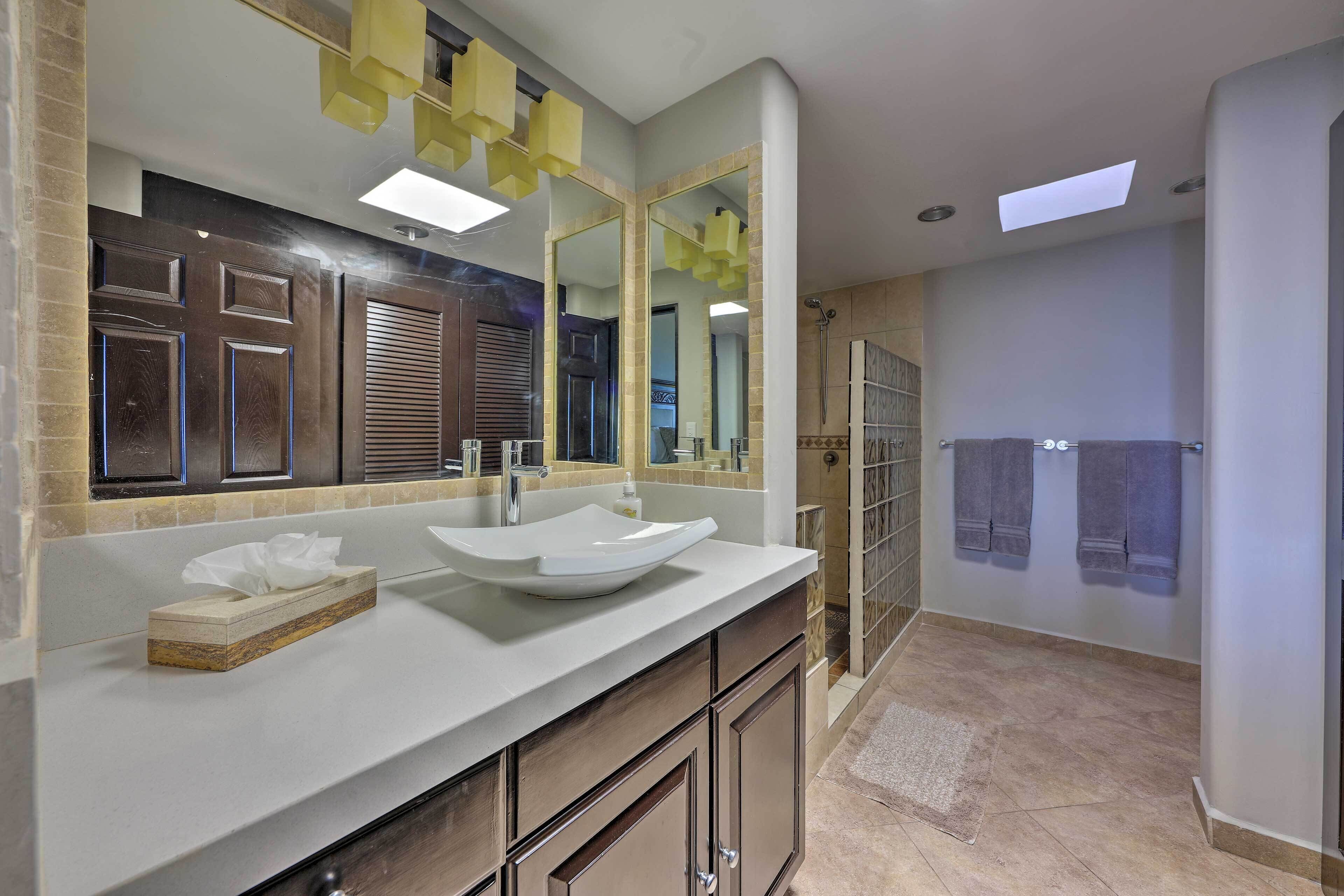 A modern bathroom with a large mirror, a white sink, and a shower area.