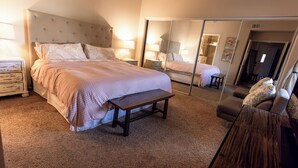 A bedroom with a bed, bedside tables, a bench, a mirror, and a wardrobe. - Central Scottsdale Location 2BR / 1.5 Bath Second Floor Spacious Unit  (Scottsdale)