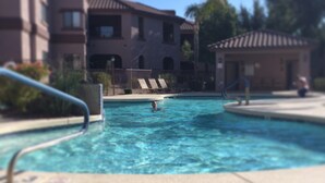 A swimming pool with a person swimming, surrounded by buildings and a clear sky. - Central Scottsdale Location 2BR / 1.5 Bath Second Floor Spacious Unit  (Scottsdale)