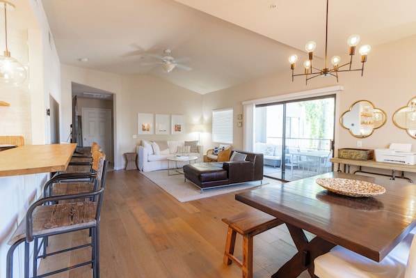 A spacious living area with a dining table, chairs, a sofa, and a ceiling fan.