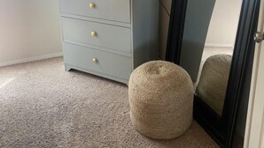A room with a light blue cabinet with gold knobs, a round beige pouf, and a black-framed mirror. - Central Scottsdale Location 2BR / 1.5 Bath Second Floor Spacious Unit  (Scottsdale)