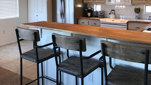 A kitchen with a central island, bar stools, stainless steel appliances, and pendant lighting. - Central Scottsdale Location 2BR / 1.5 Bath Second Floor Spacious Unit  (Scottsdale)