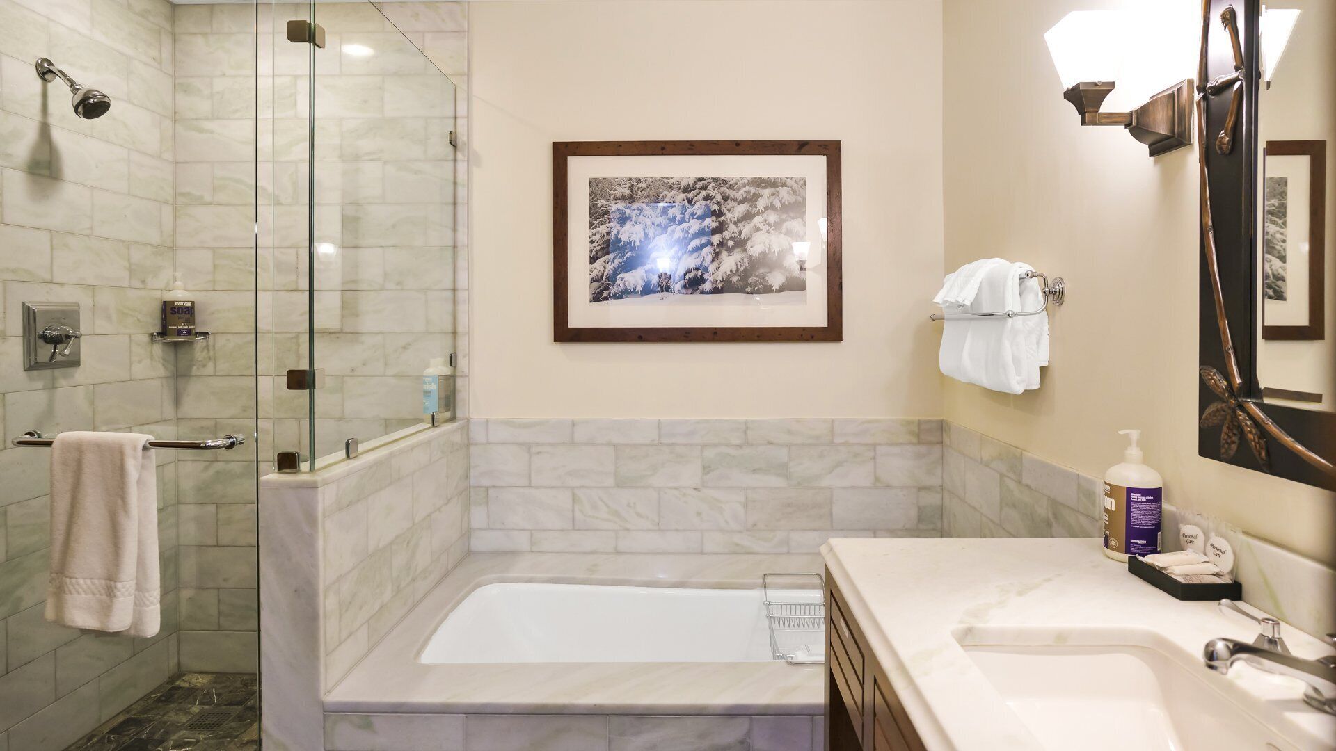A bathroom with a glass-enclosed shower, a bathtub, and a vanity with a sink and mirror.