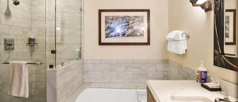 A bathroom with a glass-enclosed shower, a bathtub, and a vanity with a sink and mirror.