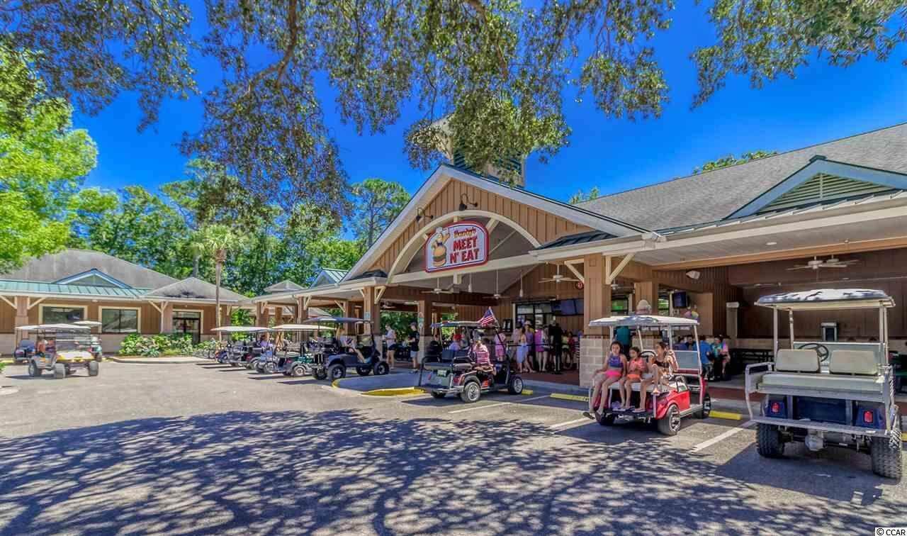 A restaurant with a 'Meet N Eat' sign, outdoor seating, and golf carts.