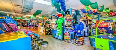 An arcade with various gaming machines, including a green whale-themed game and a blue racing game.