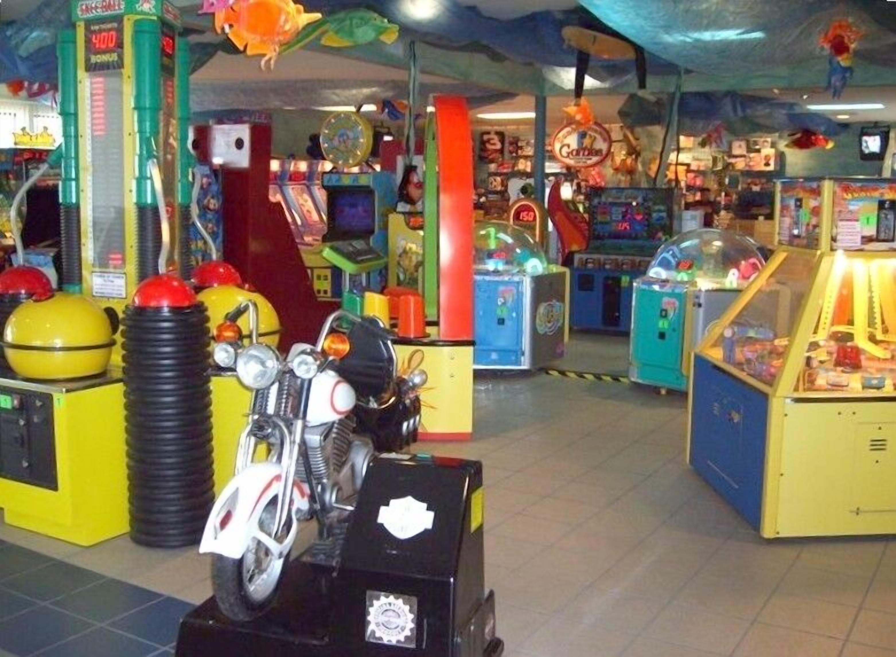 An arcade with various gaming machines, including a motorcycle game.