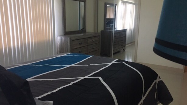 Une chambre à coucher avec un lit, une commode et un miroir.