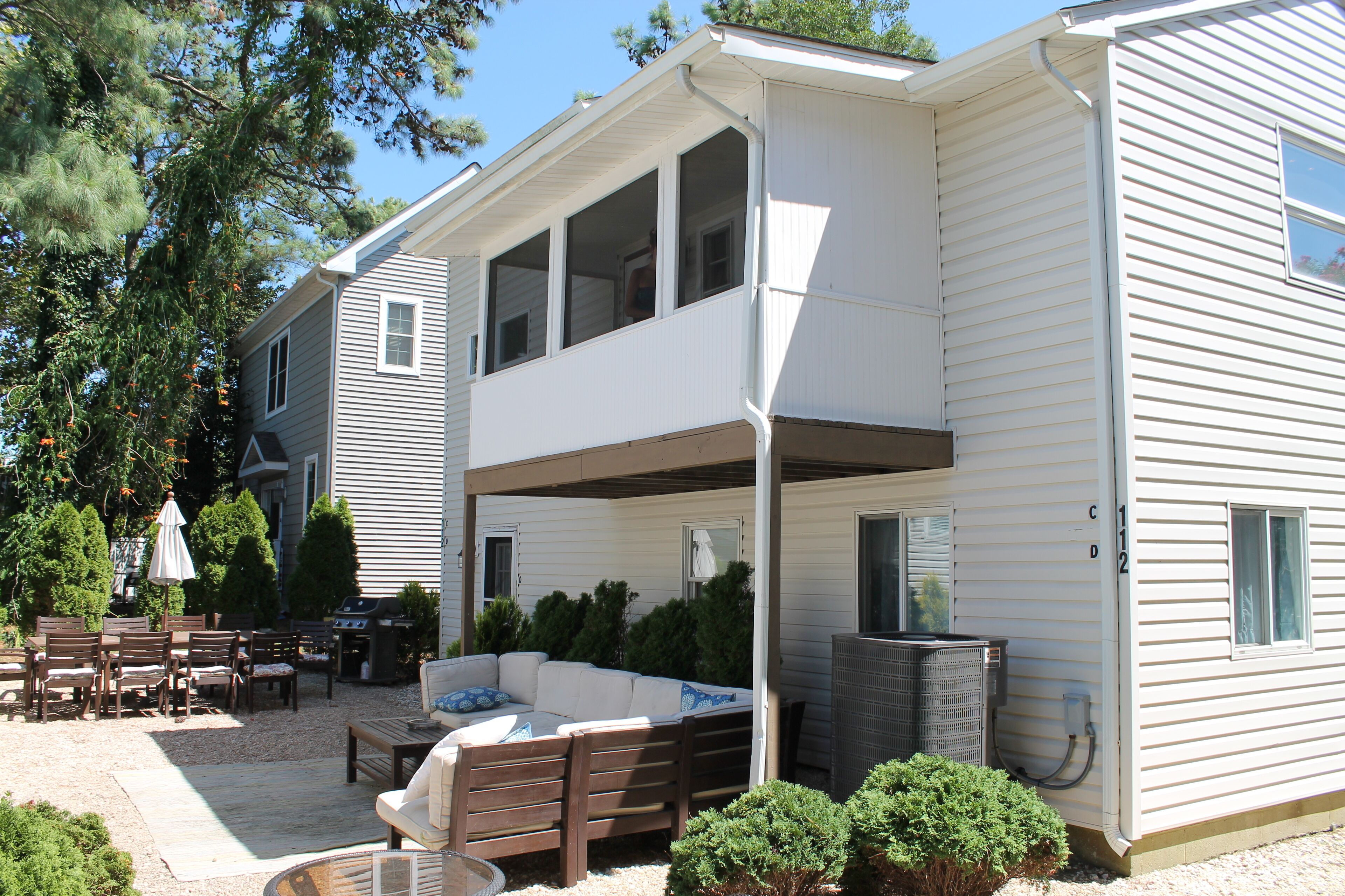 A two-story house with a covered patio, outdoor furniture, and a grill area.