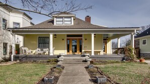 A two-story house with a front porch, a front door, and a small garden area with a pathway leading to the entrance.