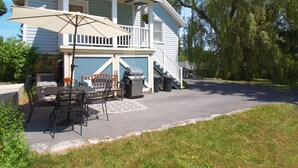 A two-story house with a covered patio, outdoor seating, and a barbecue grill.