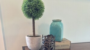 A wooden table with a potted plant, a decorative vase, and a woven basket.