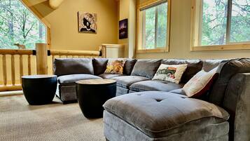 A modern living room with a sectional sofa, two round coffee tables, and a wooden railing.
