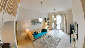 A modern living room with a sofa, coffee table, and decorative items. There is a bookshelf and a TV in the background. - LOCATION LOCATION LOCATION - Prime central London ZONE 1 (London)