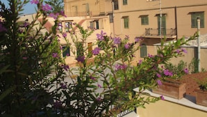 A building with multiple balconies and windows, surrounded by greenery and flowers. - Sperlinga kept - Il Campanile (Santa Flavia)