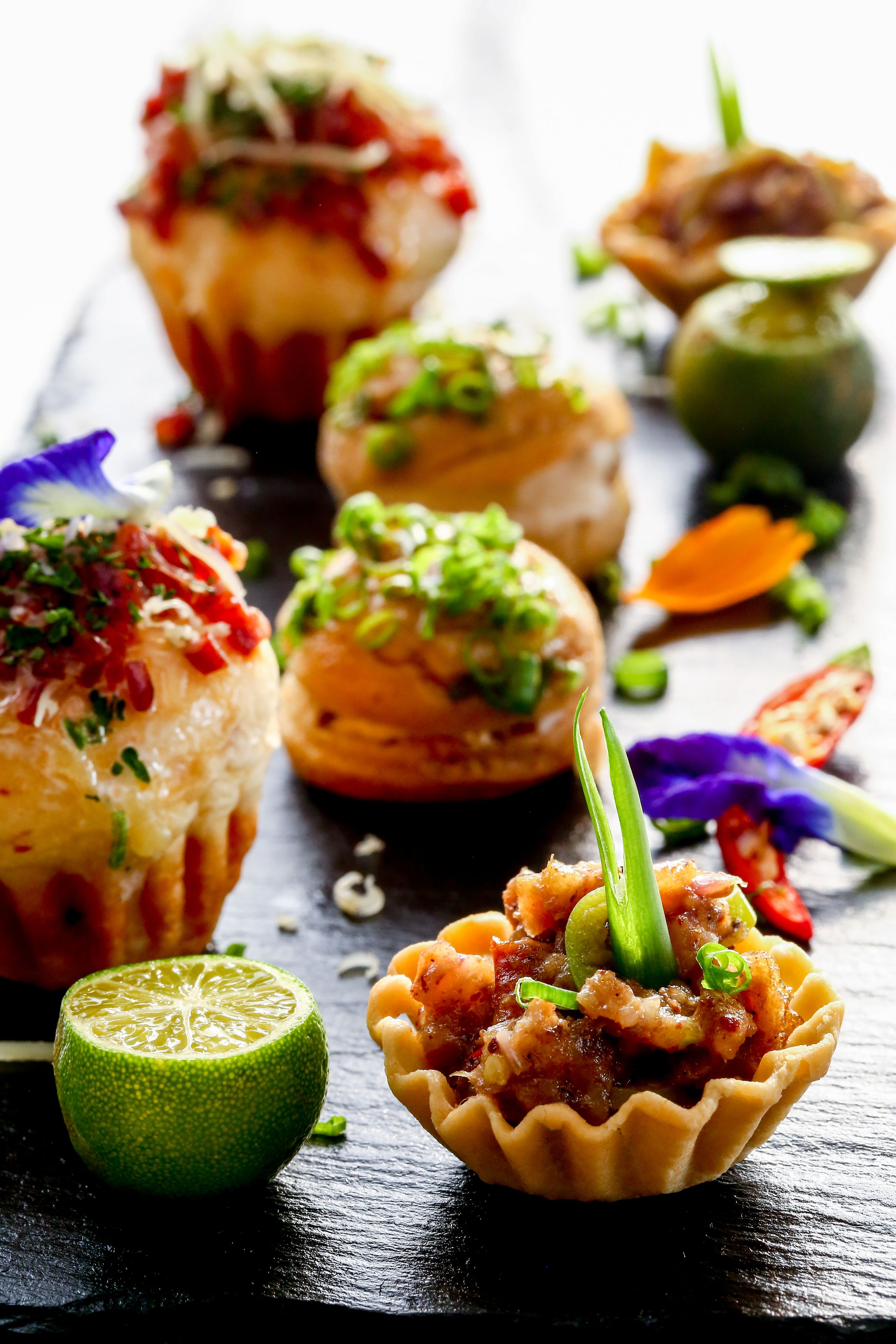 A variety of food items, including a lime, a tart, and a dish with green onions.