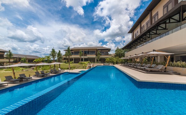 Una piscina al aire libre, sombrillas, sillones reclinables de piscina