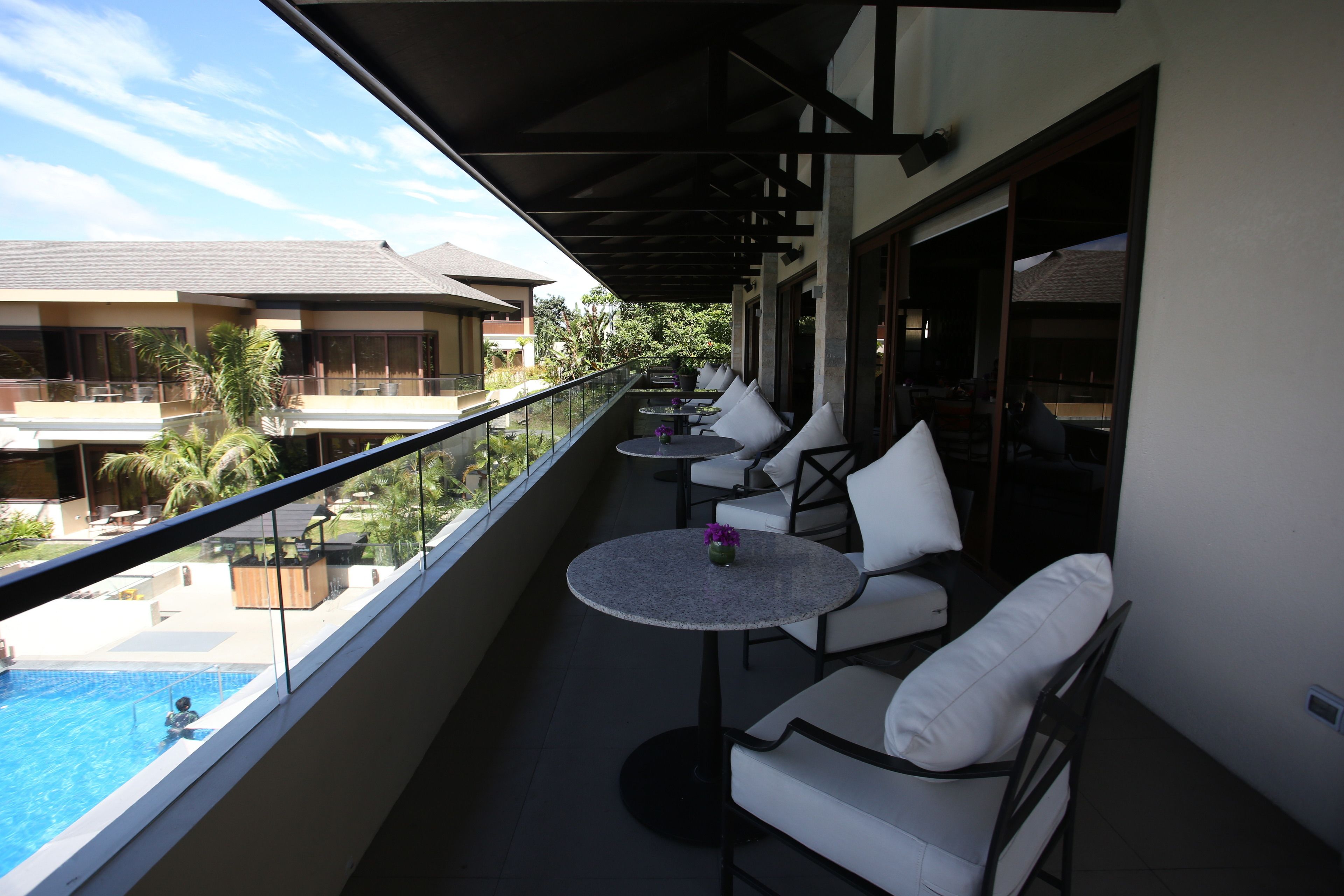 A balcony with outdoor seating and a view of a swimming pool.
