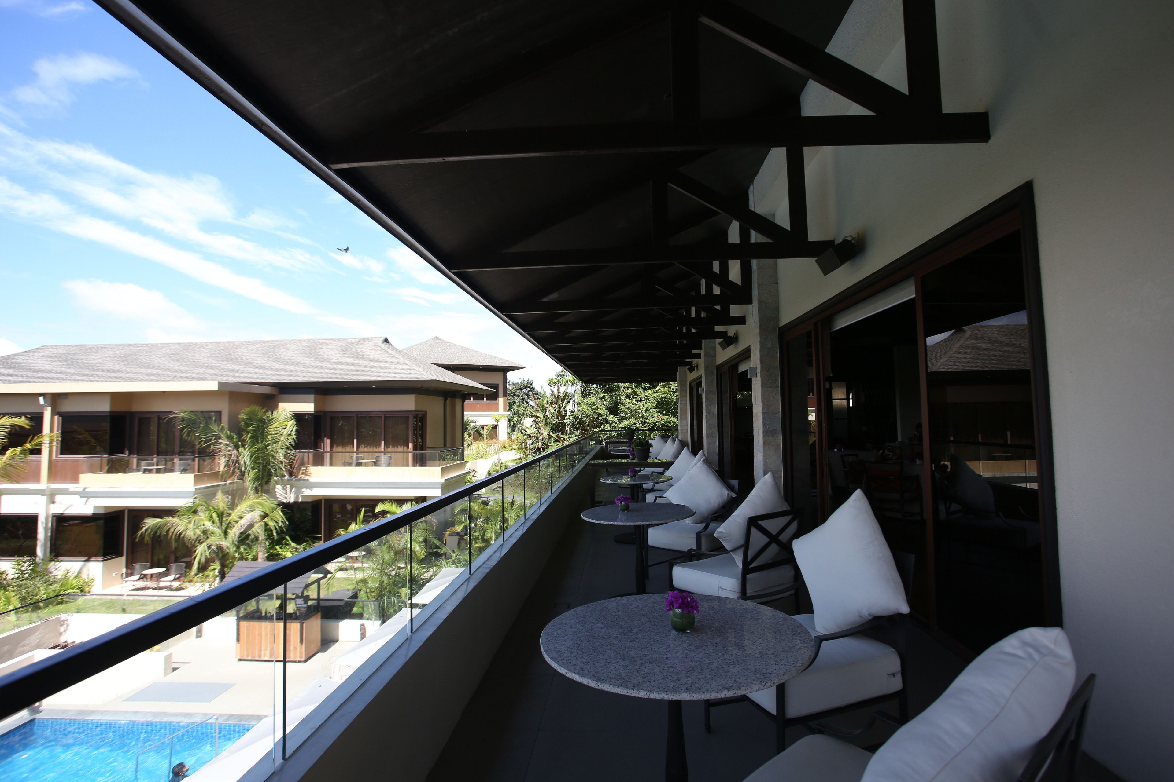 Ein Balkon mit Sitzgelegenheit im Freien, einem Pool und Blick auf andere Gebäude.