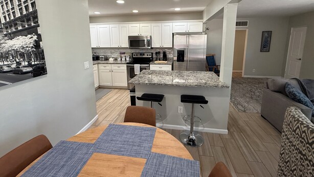 A modern kitchen with white cabinets, a stainless steel refrigerator, and a granite countertop. - Beautifully Charming Redbrick Home (Phoenix)