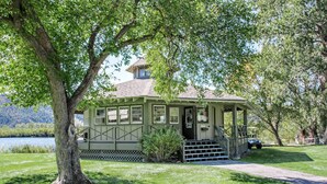 A small, single-story building with a porch, situated in a grassy area with trees and a lake in the background. - 2 BR Condo with 2 Fishing Badges! 24 Mi. to Aspen (Carbondale)