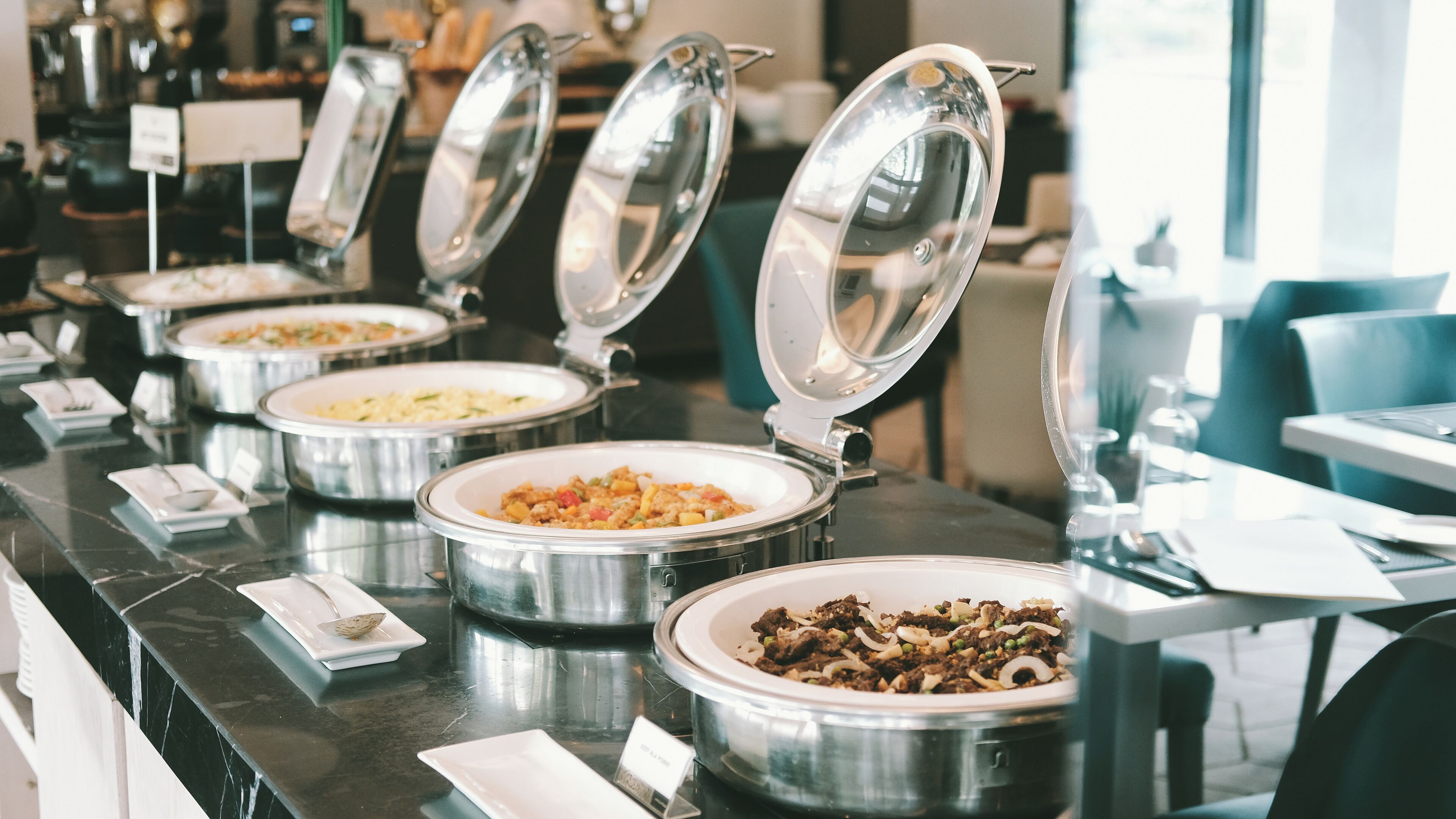 A buffet setup with multiple food containers and serving utensils.
