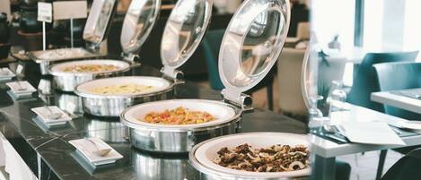 A buffet setup with multiple food containers and serving utensils.