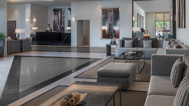 A modern hotel lobby with a reception desk, seating area, and artwork on the walls.